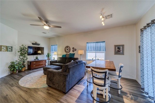 living room with dark wood-style floors, a wealth of natural light, and visible vents