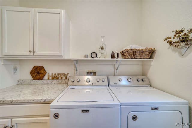 laundry room with washing machine and clothes dryer and cabinet space