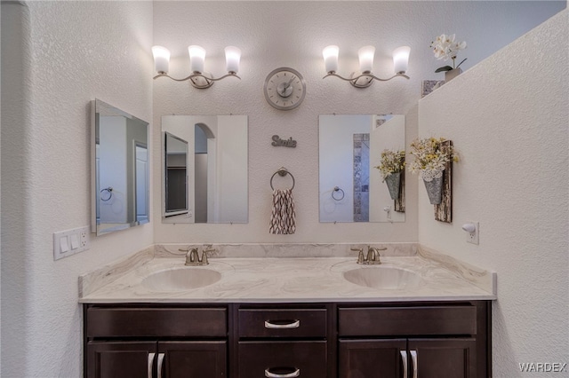 bathroom with double vanity, a sink, and a textured wall