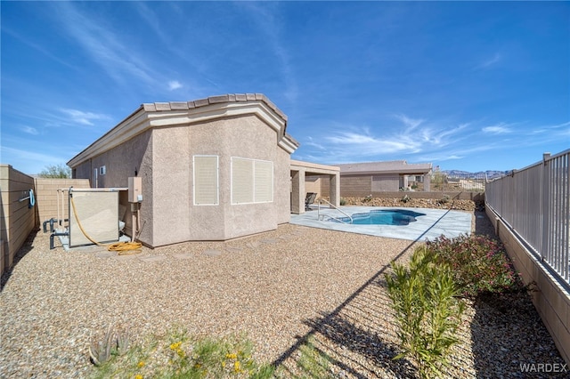 back of house with a patio, a fenced backyard, a fenced in pool, and stucco siding