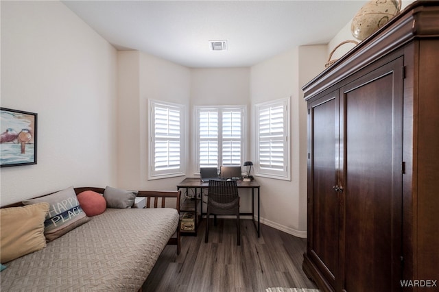 bedroom with dark wood-style floors, visible vents, and baseboards