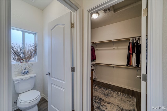 bathroom featuring visible vents, toilet, baseboards, and wood finished floors