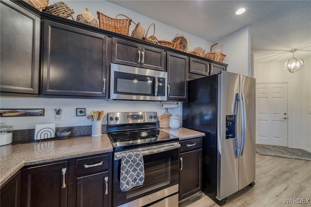 kitchen featuring dark brown cabinetry, recessed lighting, appliances with stainless steel finishes, light wood-type flooring, and an inviting chandelier