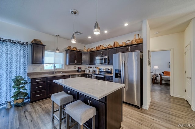 kitchen featuring visible vents, a center island, hanging light fixtures, stainless steel appliances, and a sink