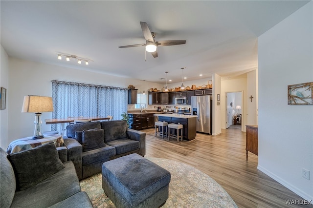 living room featuring light wood finished floors, ceiling fan, baseboards, and recessed lighting