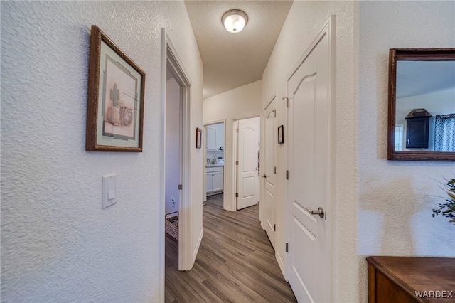 hall with wood finished floors and a textured wall