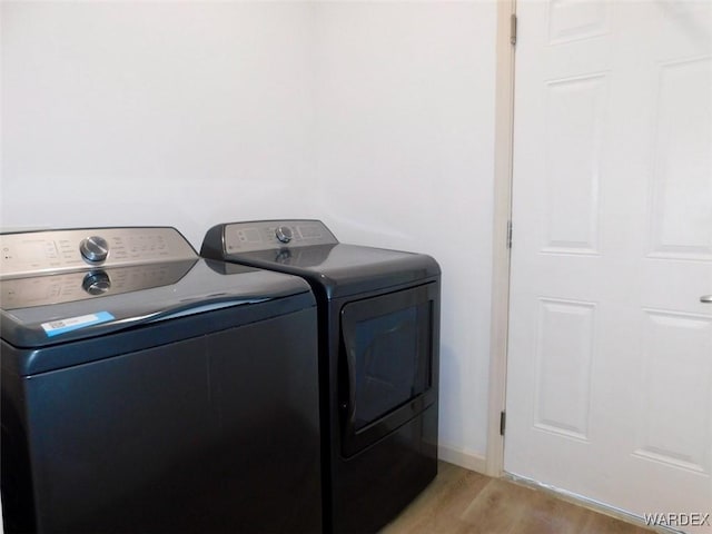 laundry room with baseboards, laundry area, washer and clothes dryer, and light wood-style floors