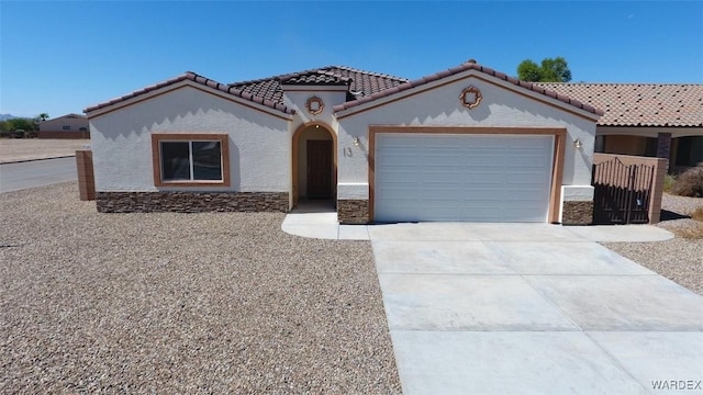 mediterranean / spanish house with driveway, an attached garage, a tile roof, and stucco siding