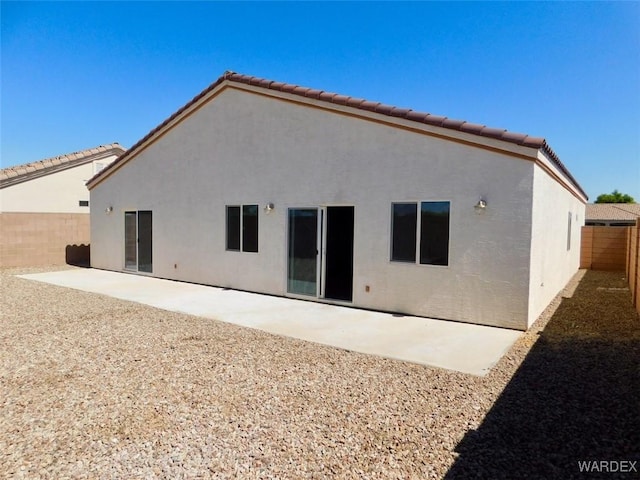 back of house featuring a tiled roof, a patio area, a fenced backyard, and stucco siding