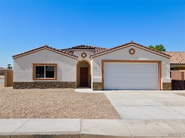 mediterranean / spanish-style house with driveway, a tiled roof, an attached garage, and stucco siding