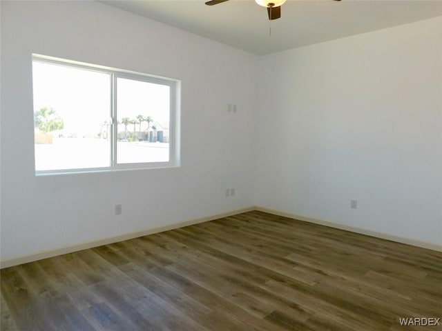 unfurnished room with dark wood-style floors, ceiling fan, and baseboards