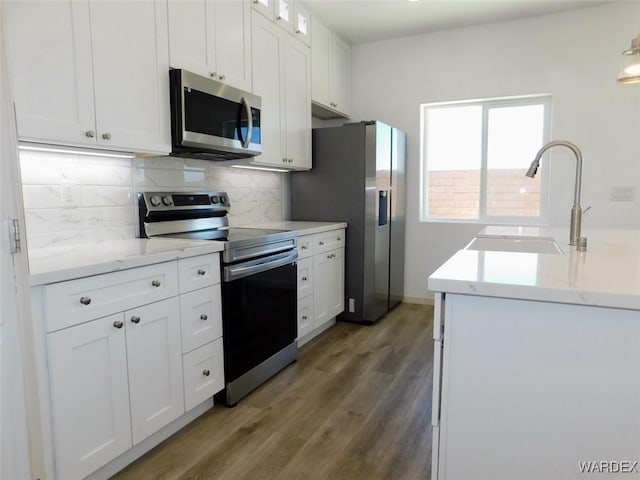 kitchen featuring stainless steel appliances, backsplash, dark wood-type flooring, white cabinets, and a sink