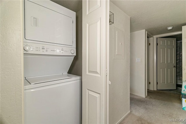 clothes washing area with stacked washer / dryer, light carpet, a textured ceiling, laundry area, and baseboards