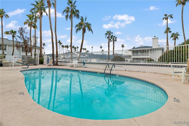 community pool with a patio area and fence