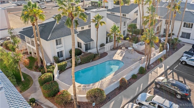 community pool featuring a patio area, stairs, a residential view, and fence