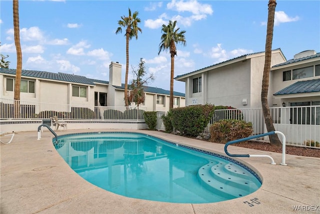 community pool with a patio area, fence, and a residential view