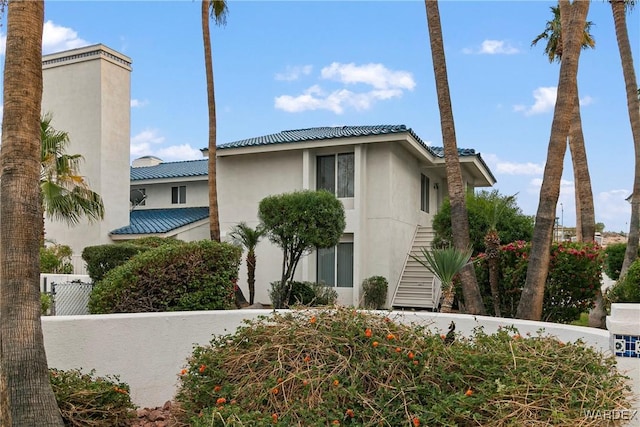 view of property exterior featuring stairway, fence, and stucco siding