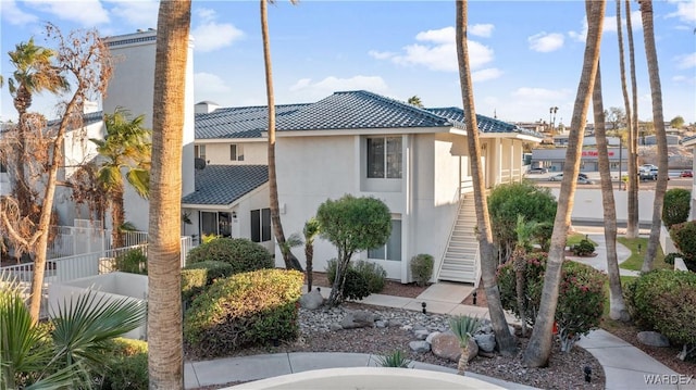 view of front of home with a tile roof, stucco siding, fence, and stairs