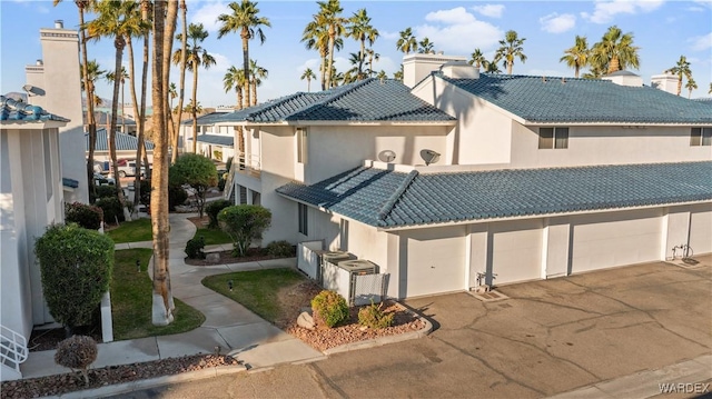 view of front facade with driveway, stucco siding, a residential view, and a tiled roof