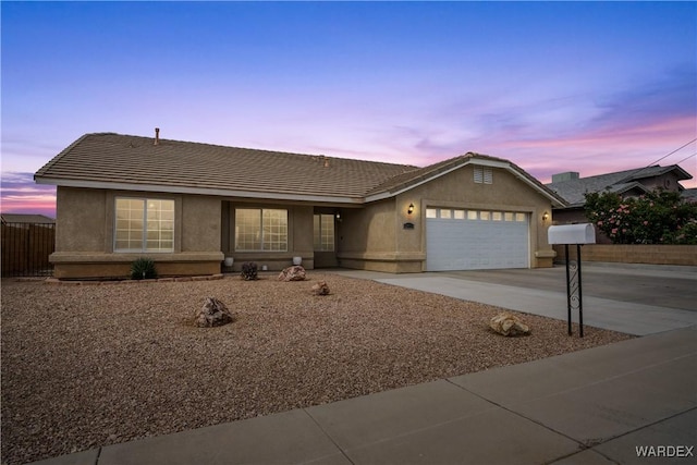 ranch-style home with a tiled roof, fence, an attached garage, and driveway