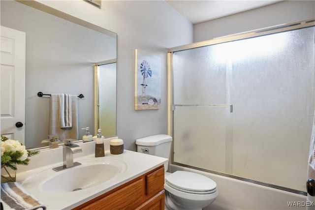 bathroom featuring vanity, combined bath / shower with glass door, and toilet