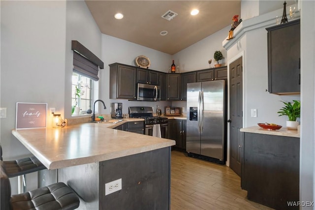 kitchen featuring appliances with stainless steel finishes, a sink, light countertops, a peninsula, and visible vents