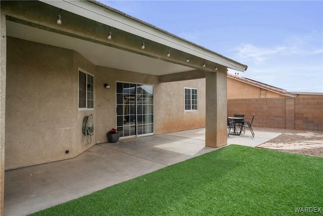 back of property featuring stucco siding, a patio area, fence, and a lawn