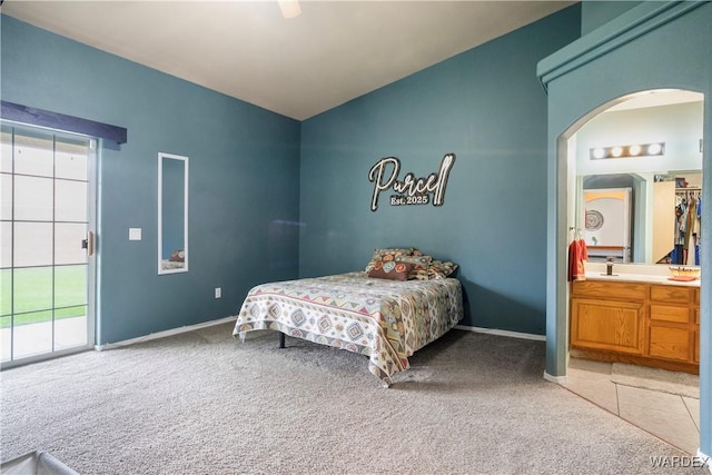 carpeted bedroom featuring arched walkways, multiple windows, ensuite bathroom, and vaulted ceiling