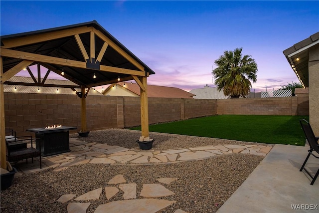 yard at dusk with a patio, a gazebo, a fire pit, and a fenced backyard