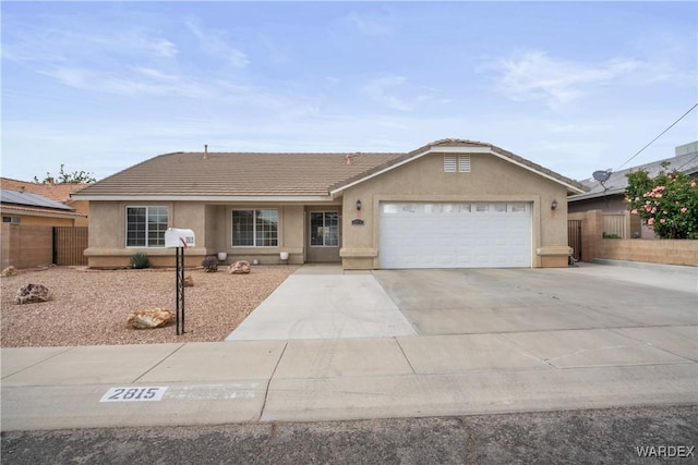 ranch-style home featuring concrete driveway, fence, and stucco siding