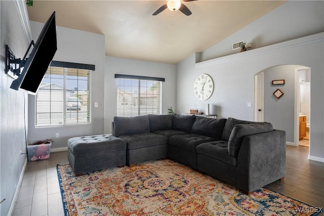 living area with arched walkways, high vaulted ceiling, a ceiling fan, baseboards, and visible vents