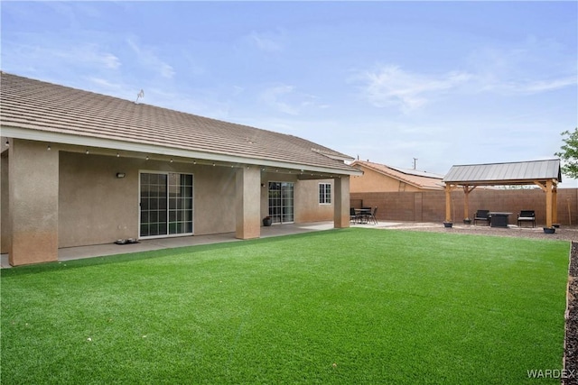 rear view of house with a patio, a gazebo, a fenced backyard, and stucco siding