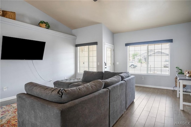 living area with baseboards, vaulted ceiling, and wood finished floors