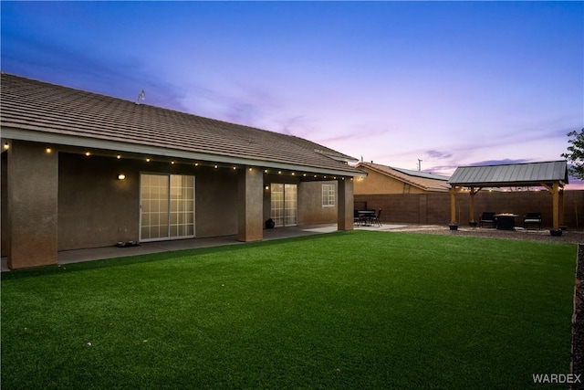 rear view of house featuring a gazebo, stucco siding, fence private yard, and a patio