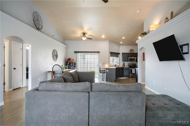 living area with a ceiling fan, arched walkways, and recessed lighting