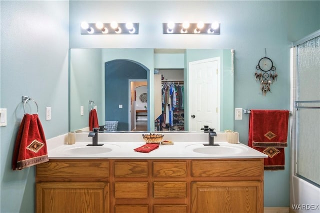 bathroom with a sink, an enclosed shower, and double vanity