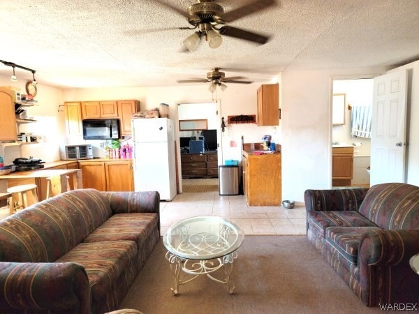 living room with light tile patterned floors, a toaster, a ceiling fan, and a textured ceiling