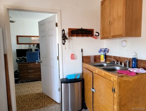 kitchen with light floors, brown cabinetry, and a sink