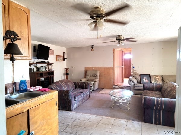 living room with a textured ceiling, light tile patterned floors, light carpet, and a ceiling fan