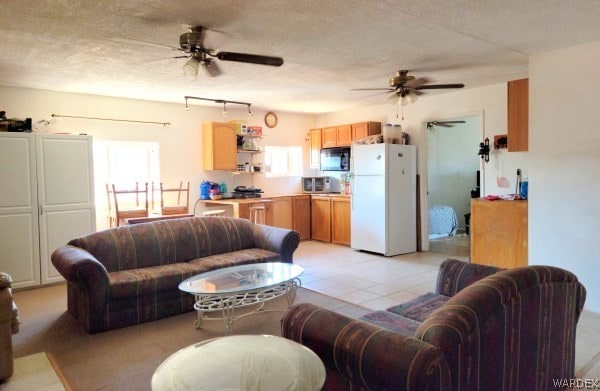 living room with a ceiling fan, light tile patterned flooring, and a textured ceiling