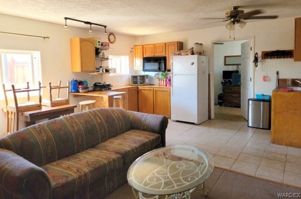 kitchen featuring freestanding refrigerator, black microwave, light countertops, and a textured ceiling