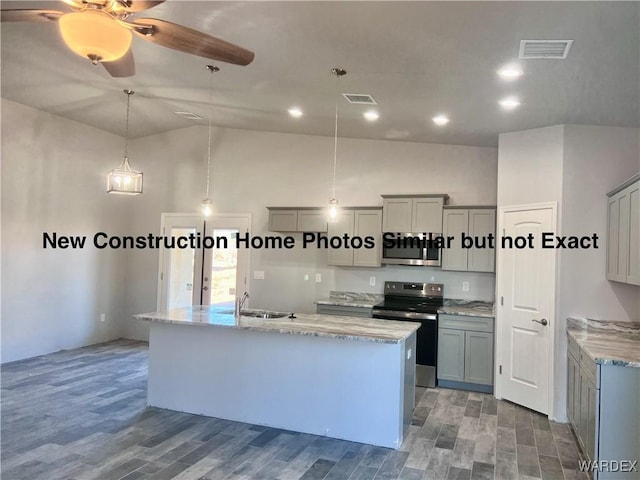 kitchen featuring visible vents, hanging light fixtures, appliances with stainless steel finishes, and a kitchen island with sink