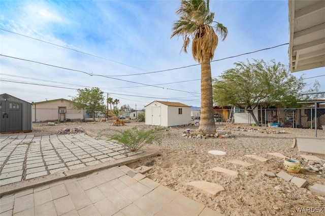 view of yard featuring a patio area, fence, a storage unit, and an outbuilding