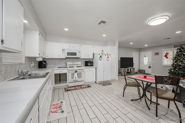 kitchen featuring white appliances, visible vents, white cabinets, light countertops, and backsplash