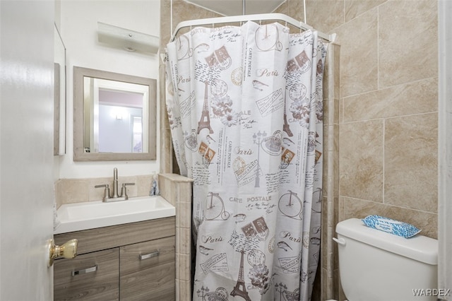 bathroom with vanity, a tile shower, toilet, and tile walls