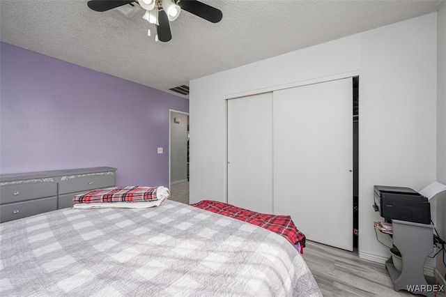 bedroom with visible vents, a ceiling fan, light wood-style flooring, a textured ceiling, and a closet