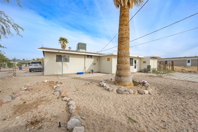 back of house with cooling unit, fence, and stucco siding