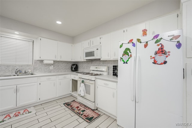 kitchen featuring white appliances, light countertops, a sink, and white cabinetry