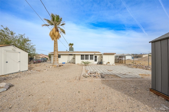 rear view of house with an outbuilding, a patio, a storage shed, and fence