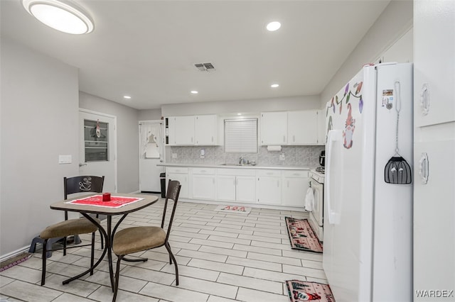 kitchen with light countertops, visible vents, decorative backsplash, white cabinetry, and white appliances